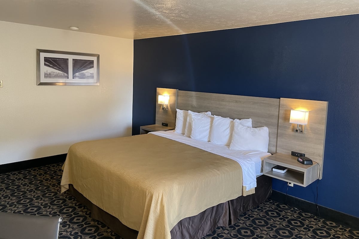 A hotel room with a bed, bedside tables, and a wall-mounted picture.