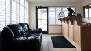 A room with a black leather sofa, a wooden counter with a bird sculpture, and a door leading outside. - Americas Best Value Inn Roosevelt Ballard (Roosevelt)