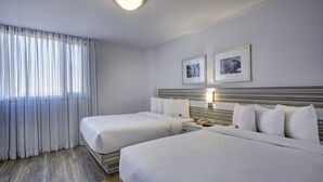 A hotel room with two beds, a bedside table with a lamp, and two framed pictures on the wall. - Town Inn Suites Hotel (Toronto)
