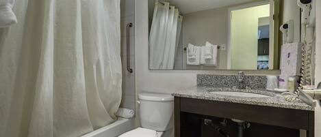 A modern bathroom with a shower, toilet, sink, and a mirror above the sink.