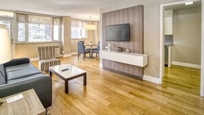 A modern living room with a sofa, coffee table, TV, and dining area. - Town Inn Suites Hotel (Toronto)