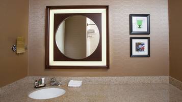 A bathroom with a large mirror, a sink, and two framed pictures on the wall.