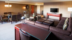 A hotel room with a dining area, a sofa set, a television, and a desk.