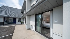 L’extérieur d’un hôtel moderne, avec un espace extérieur couvert, une entrée avec une porte-fenêtre coulissante et un numéro de chambre, le 127, bien visible.