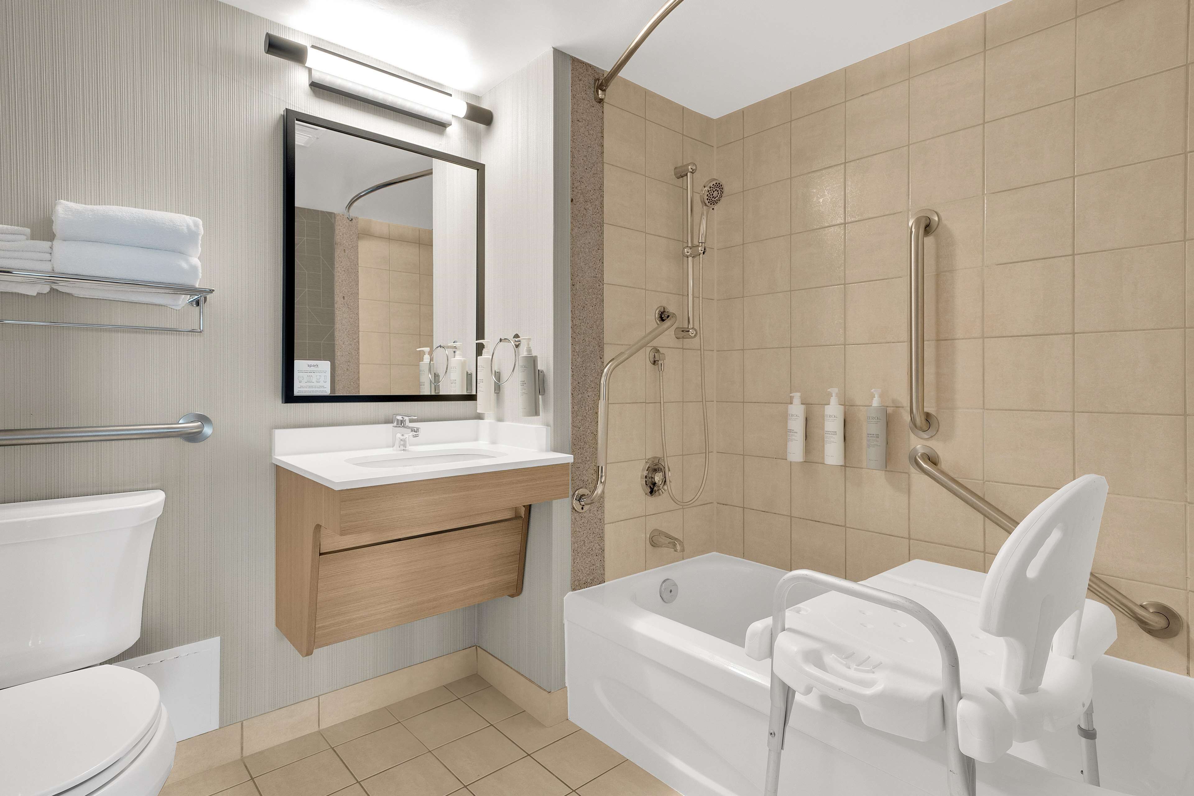 A modern bathroom with a bathtub, a shower, a toilet, and a vanity with a mirror and sink.