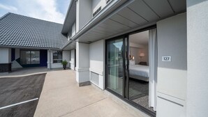 A modern hotel exterior with a covered outdoor area, a sliding glass door entrance to a room, and a visible room number 127.