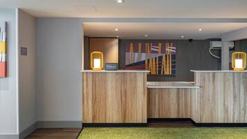 A reception area with wooden reception desks, a modern abstract painting, and a green carpet.