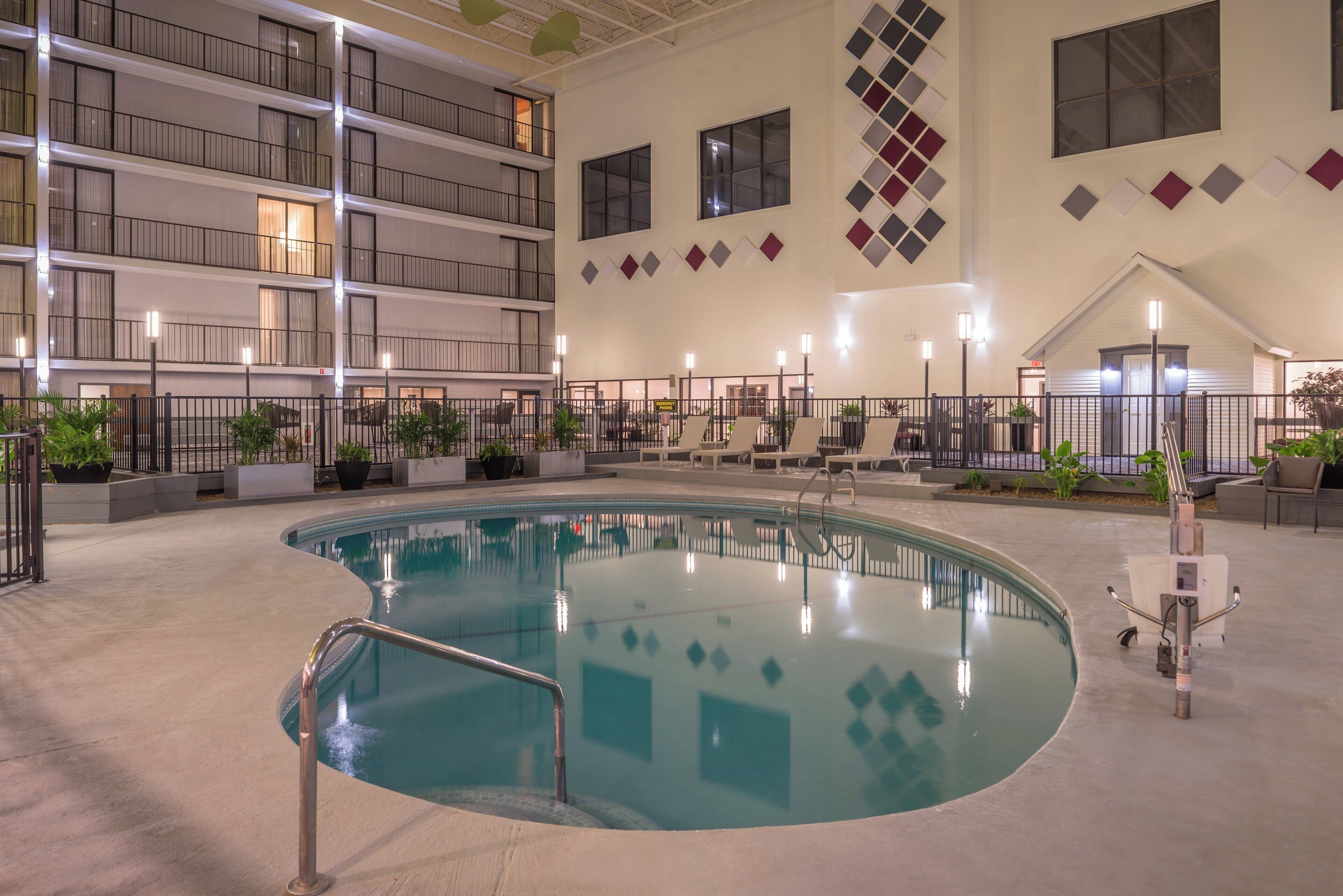 A large indoor swimming pool with a curved design, surrounded by a low fence, and multiple balconies above.