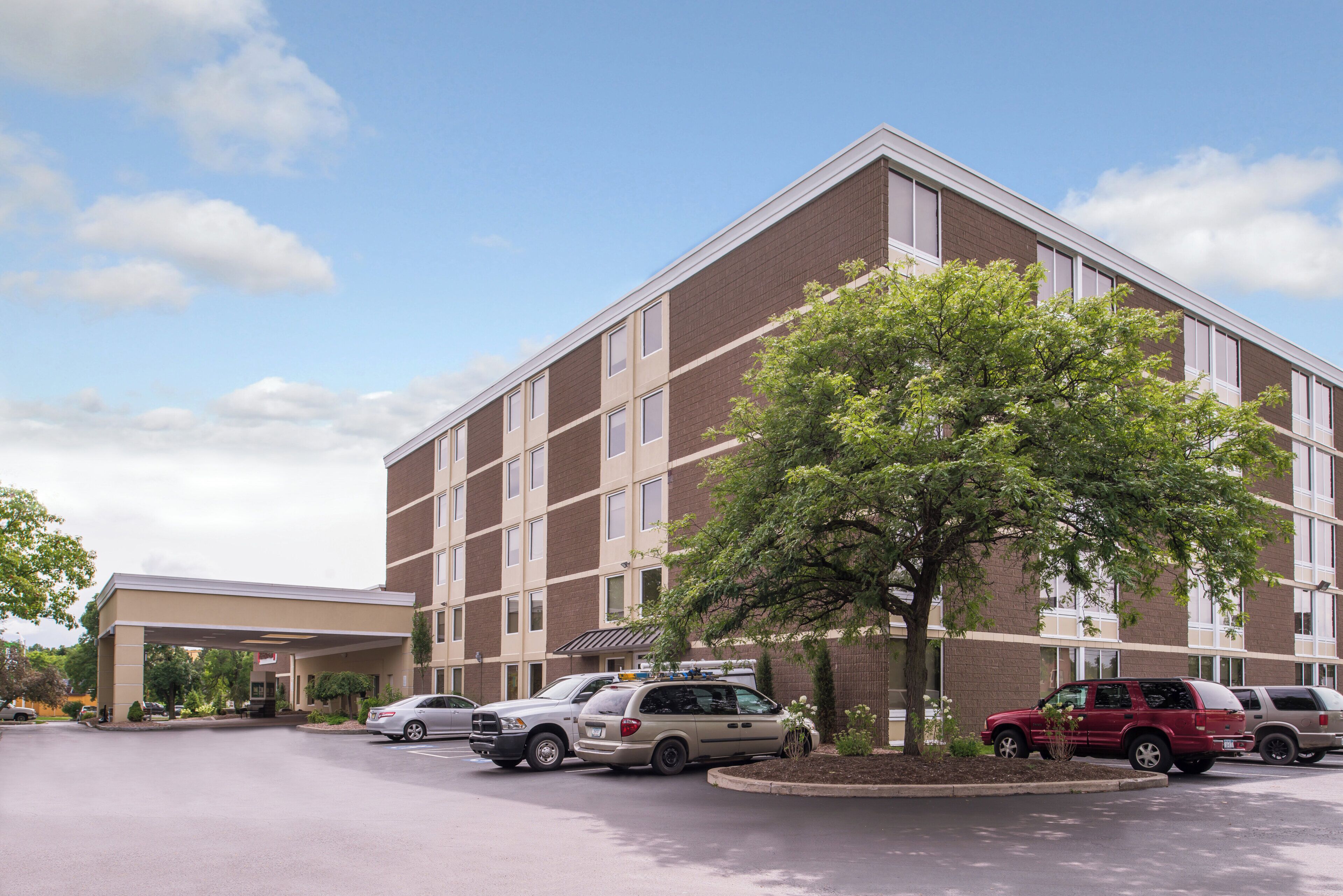 A multi-story hotel with a parking lot and a covered entrance.