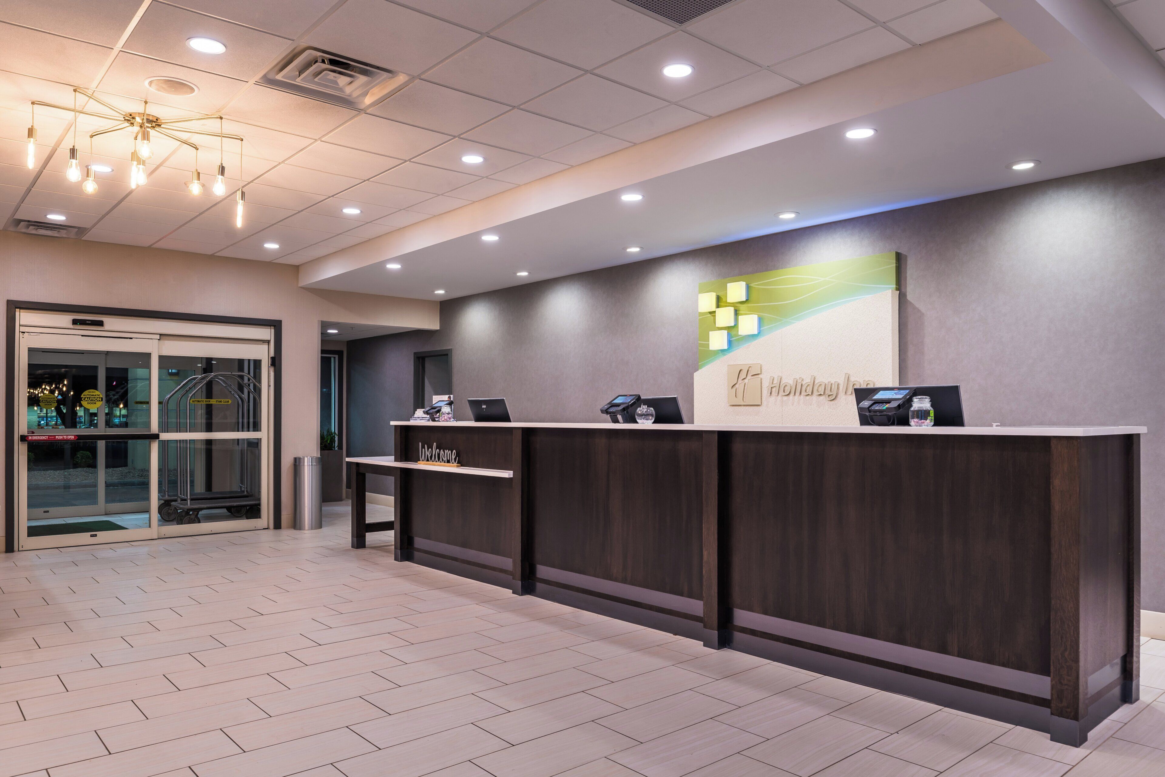 A reception desk with a 'Welcome' sign, a digital screen, and a payment terminal.