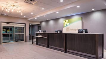 A reception desk with a 'Welcome' sign, a digital screen, and a payment terminal.