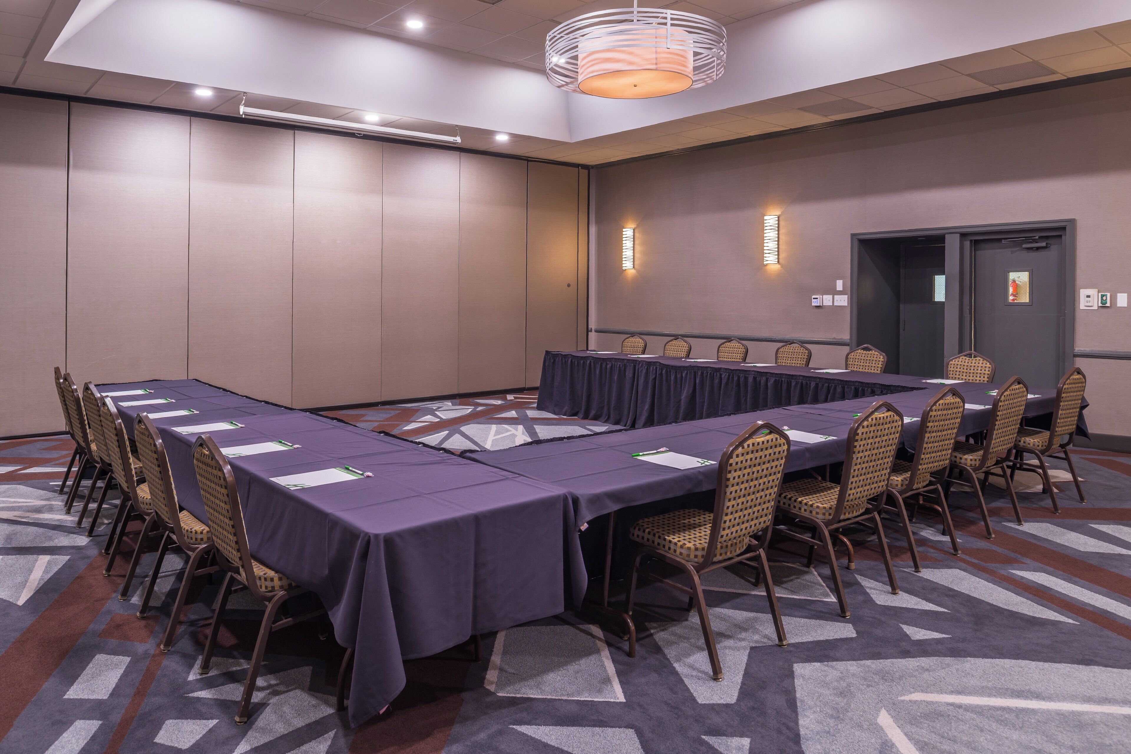 A conference room with a long table, chairs, and a carpeted floor.