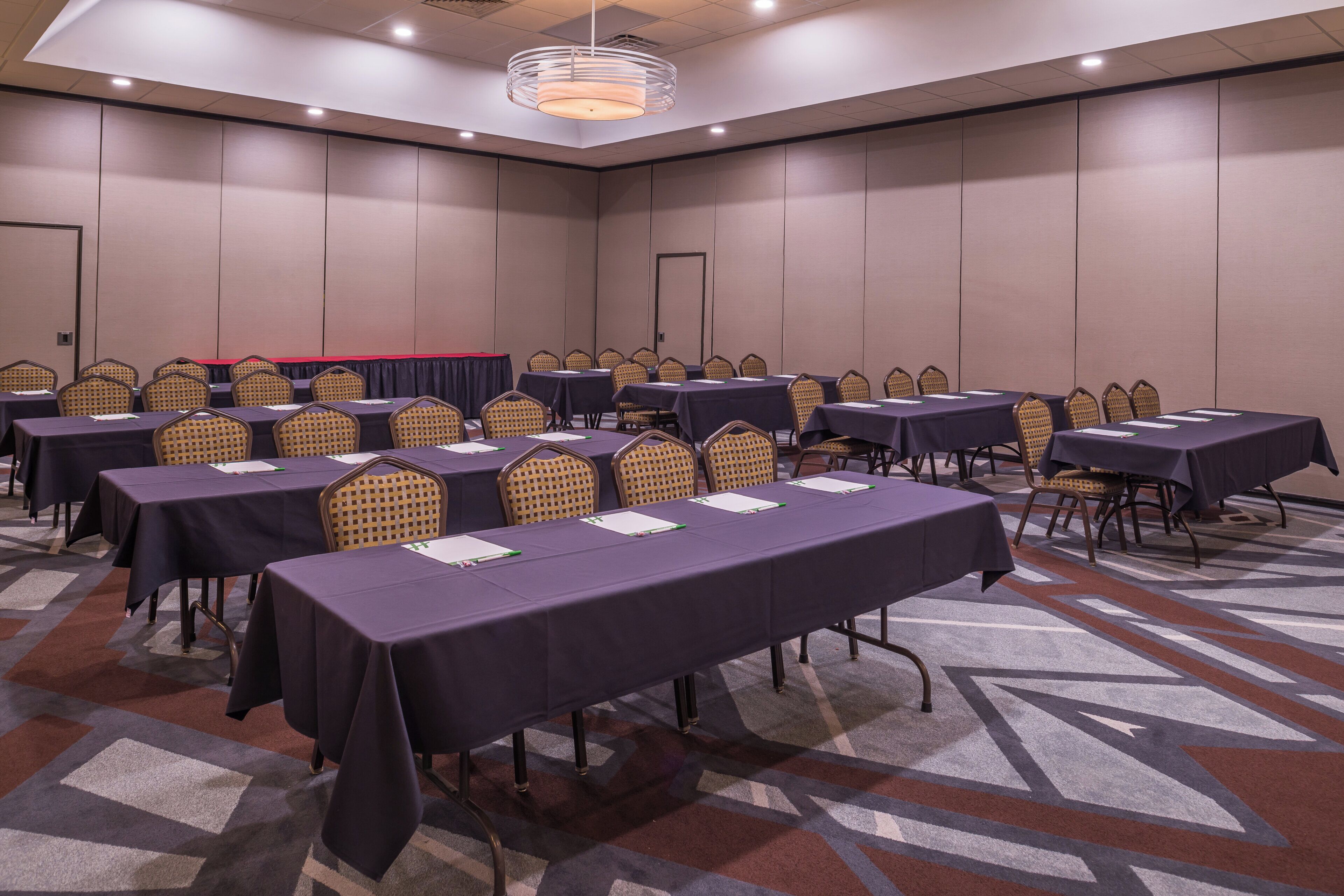 Un salón de conferencias con varias mesas y sillas dispuestas en filas.
