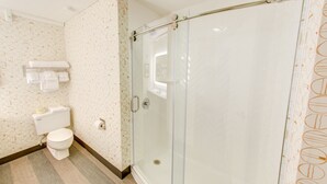Une salle de bain comprenant des toilettes, une douche à parois de verre et un porte-serviettes avec des serviettes.