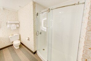 Un bagno con il water, uno spazio doccia in vetro e un portaservizi con asciugamani.