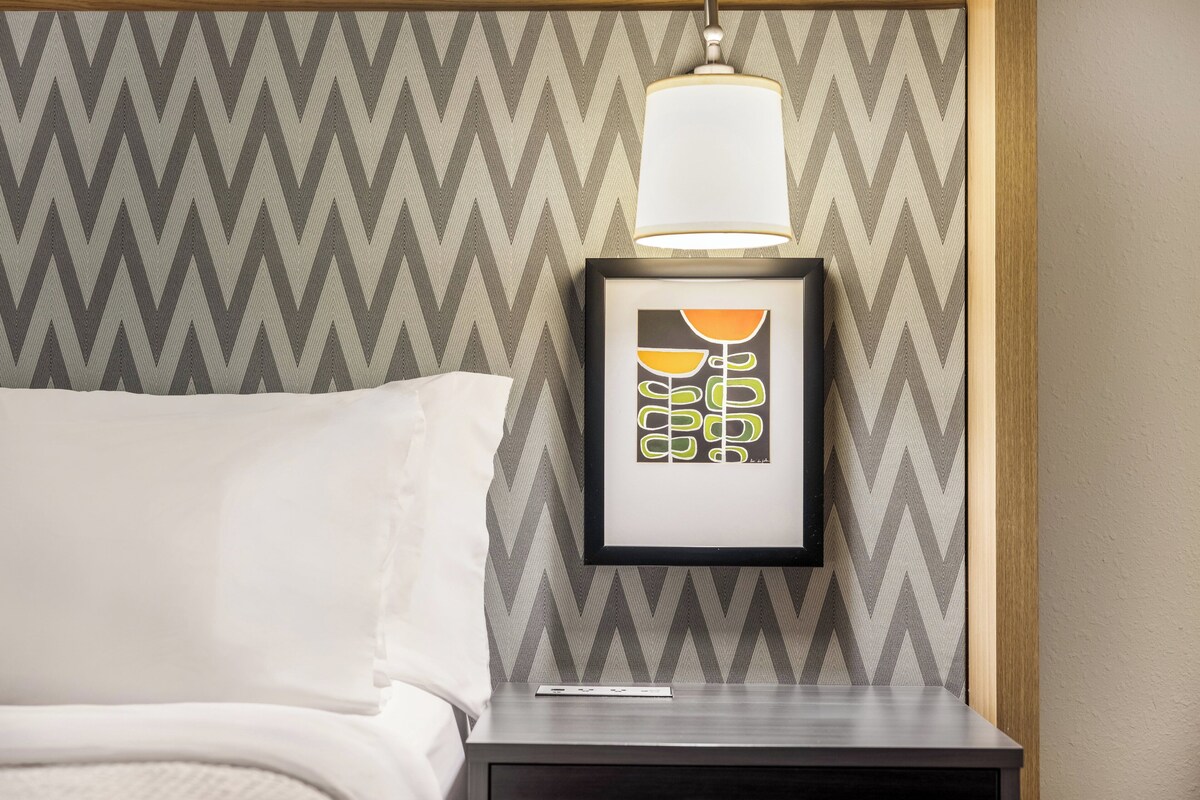 Un letto rifatto con un cuscino bianco e una cornice con un'immagine sul comodino.