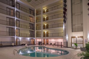 A multi-story hotel interior with a central pool area, multiple balconies, and a pool lift. - Holiday Inn Auburn-Finger Lakes Region by IHG (Auburn)