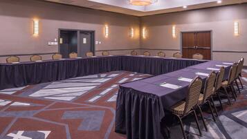 A conference room with a long table, chairs, and a patterned carpet.