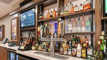 A bar area with a variety of liquor bottles, a television screen, and a bar counter.