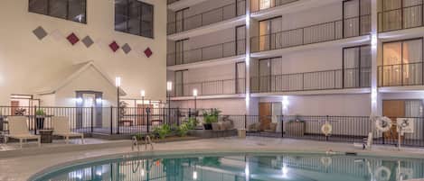 A hotel interior with a swimming pool, multiple balconies, and a covered outdoor seating area.