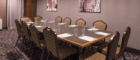 A conference room with a long table, chairs, and a carpeted floor.