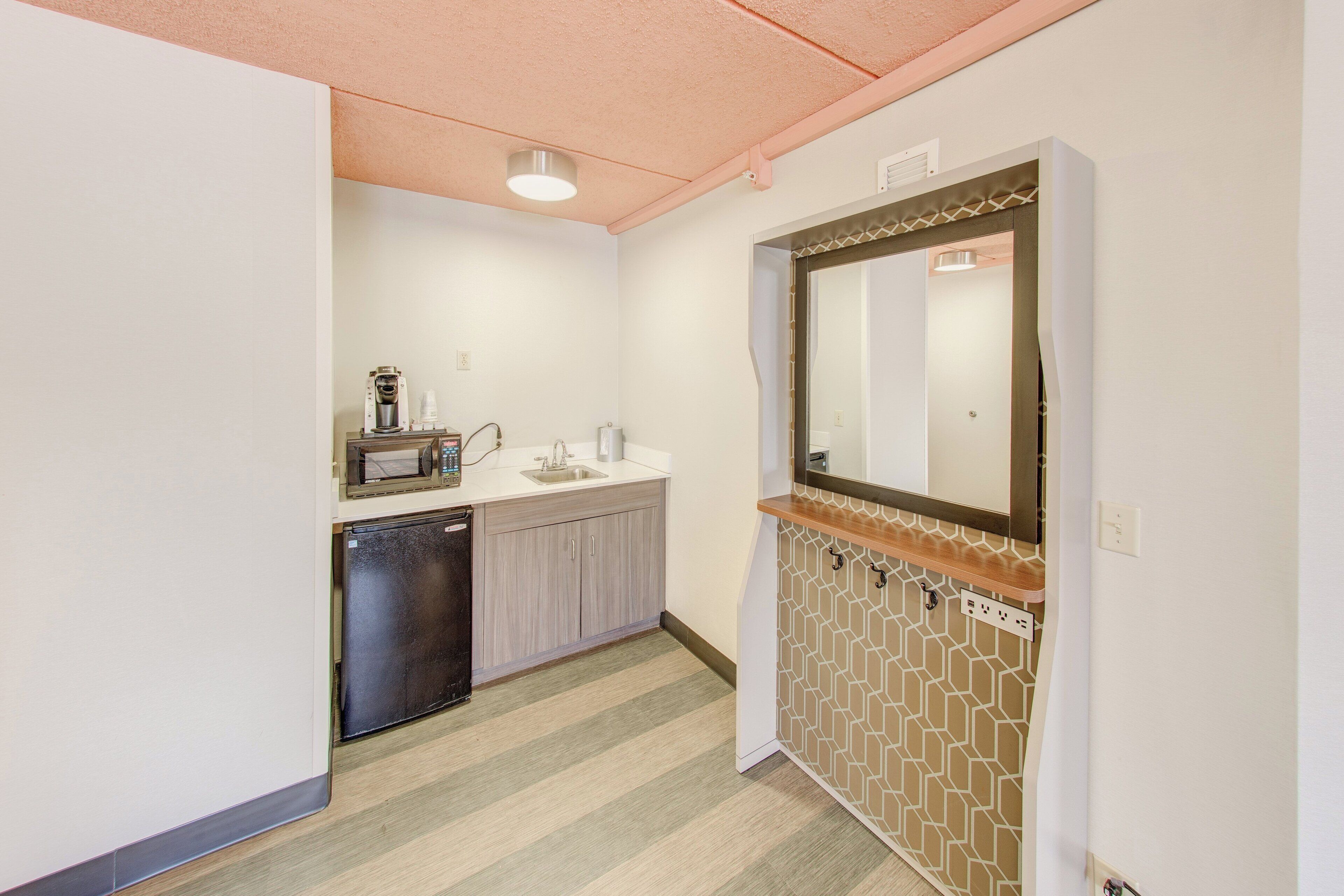 A compact kitchenette with a microwave, coffee maker, and sink.