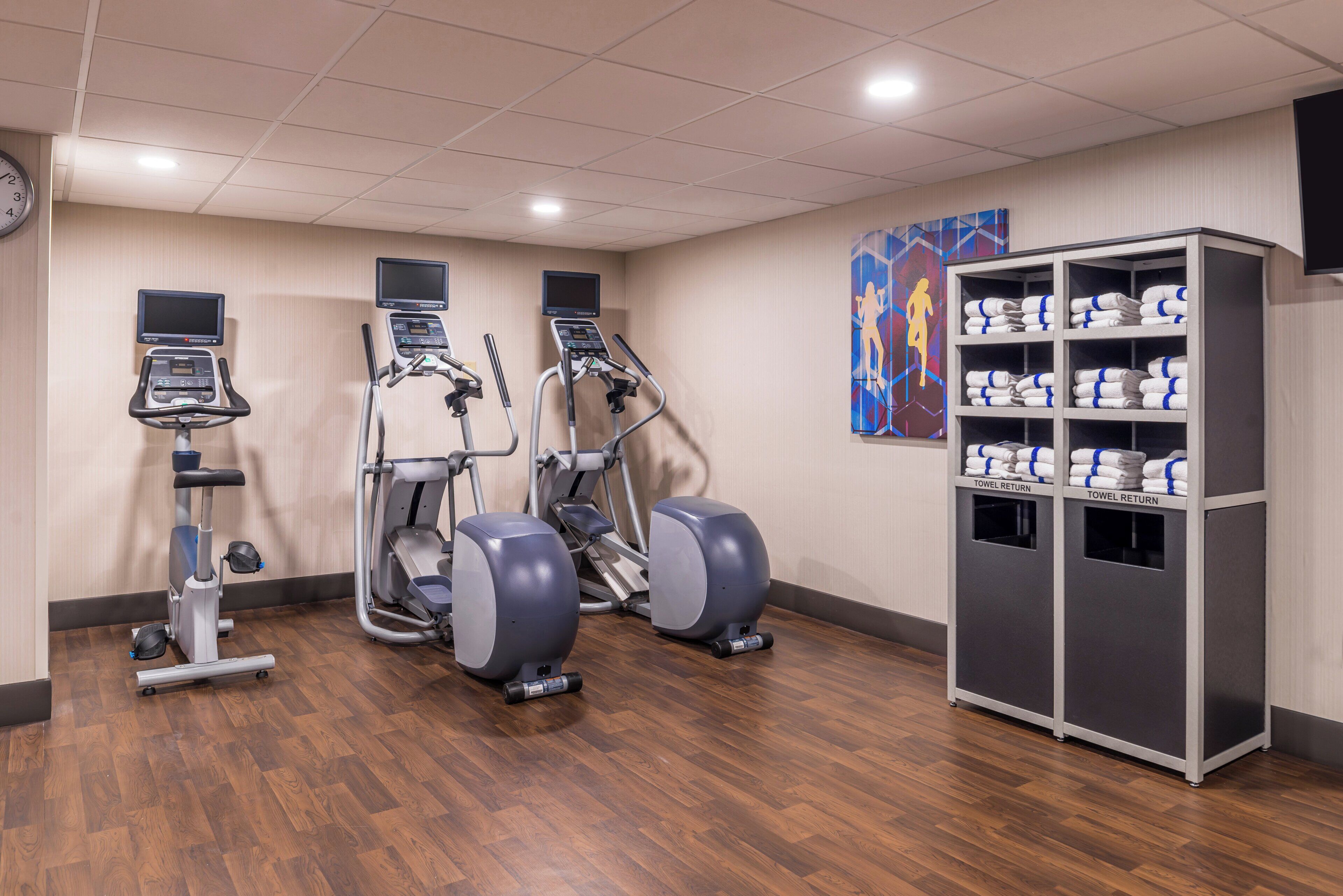 A fitness center with treadmills, elliptical machines, and a towel return station.