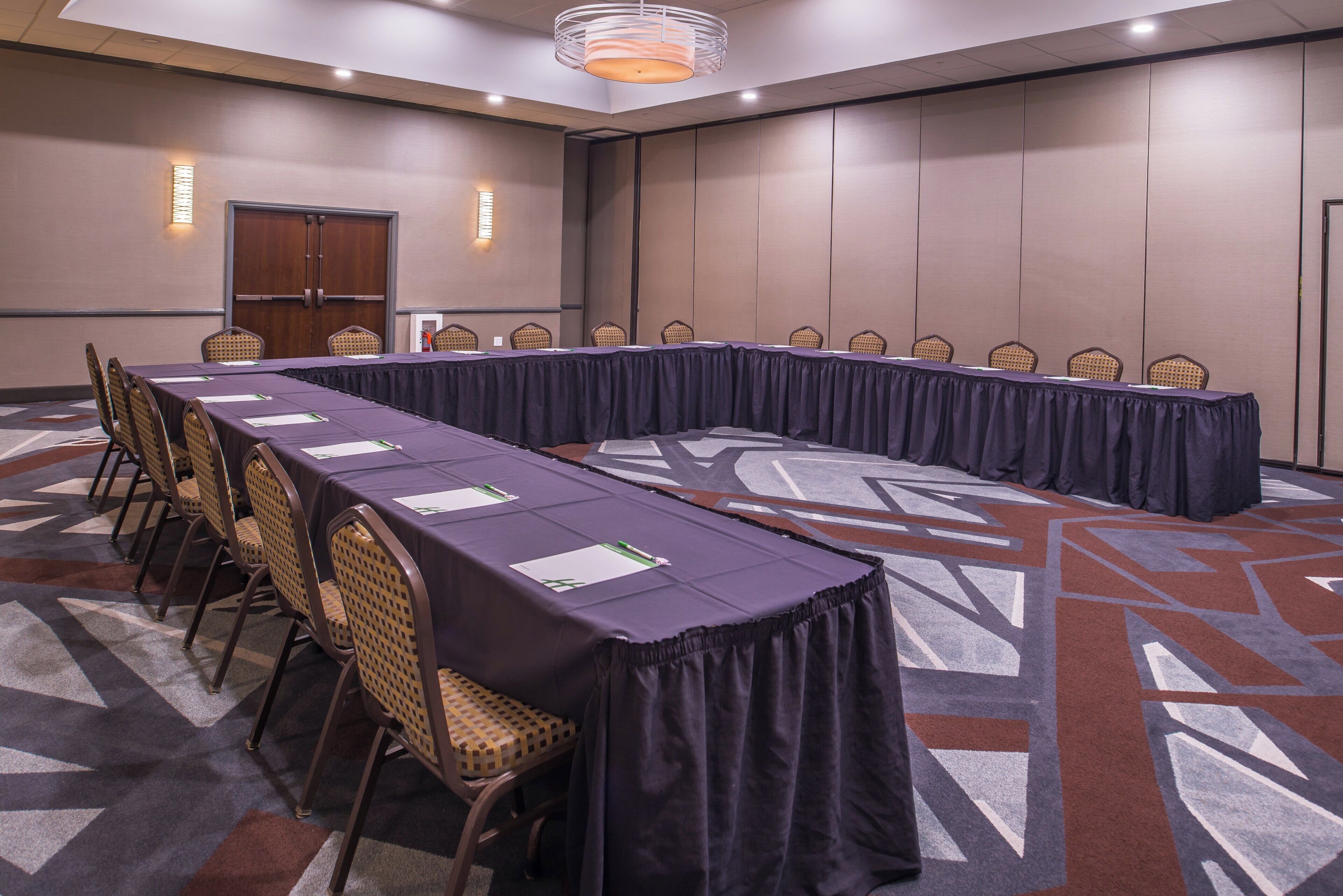A conference room with a long table, chairs, and a patterned carpet.