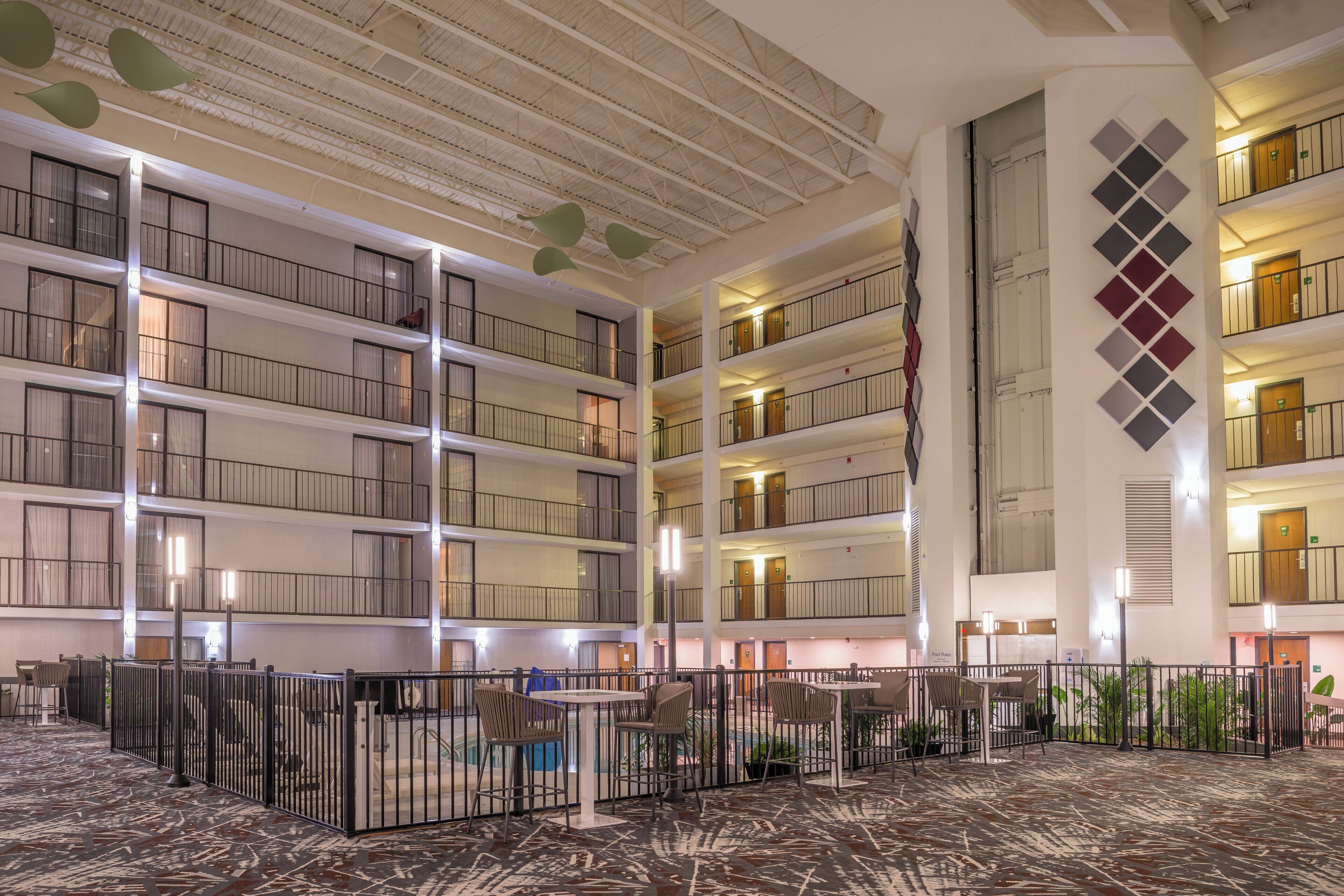 A multi-level hotel lobby with a central atrium, a flag, and a pool area.