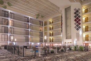 Um hall de hotel de vários níveis com um átrio central, uma bandeira e área de piscina.