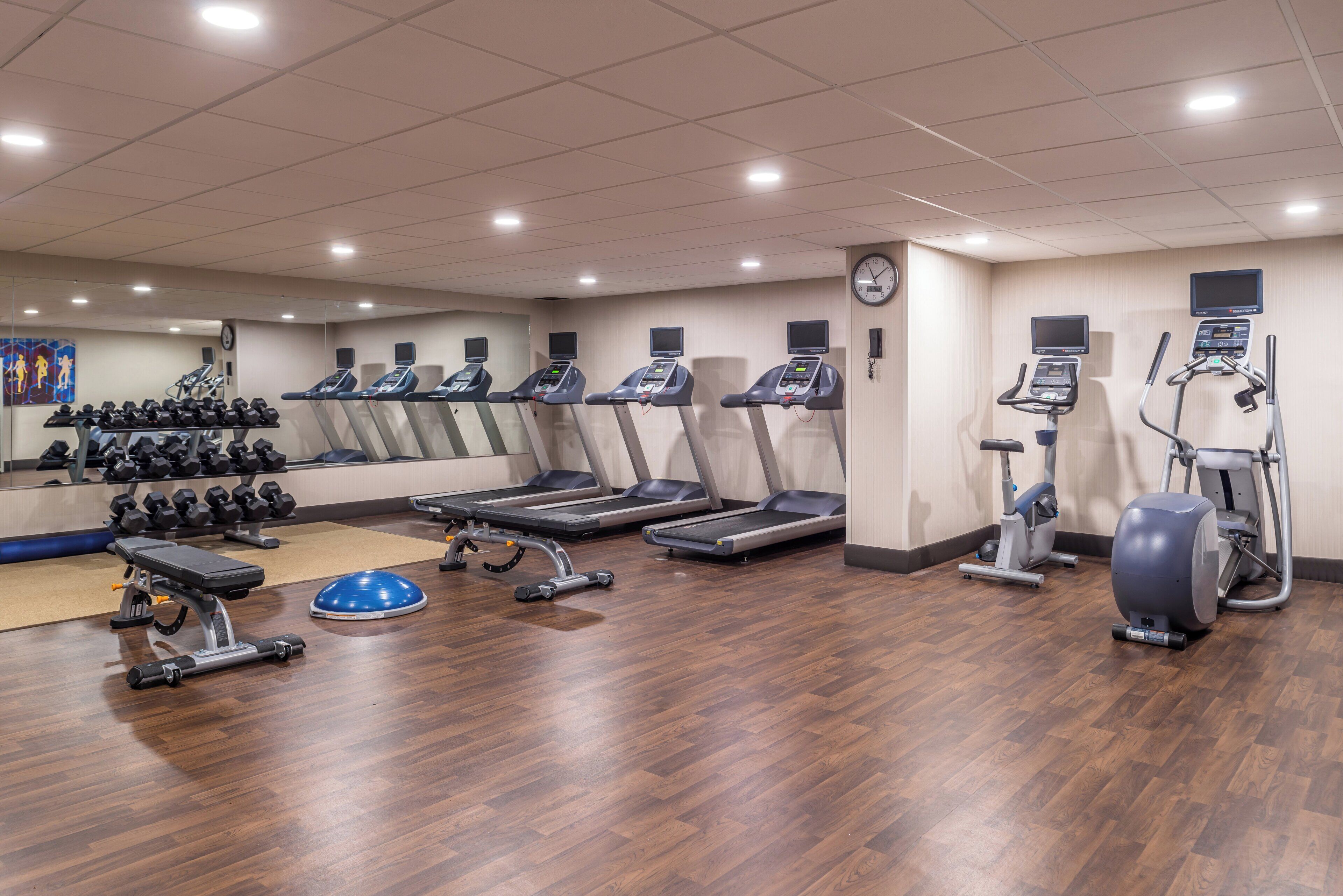 Un gimnasio con cintas de correr, elípticas y pesas sueltas.