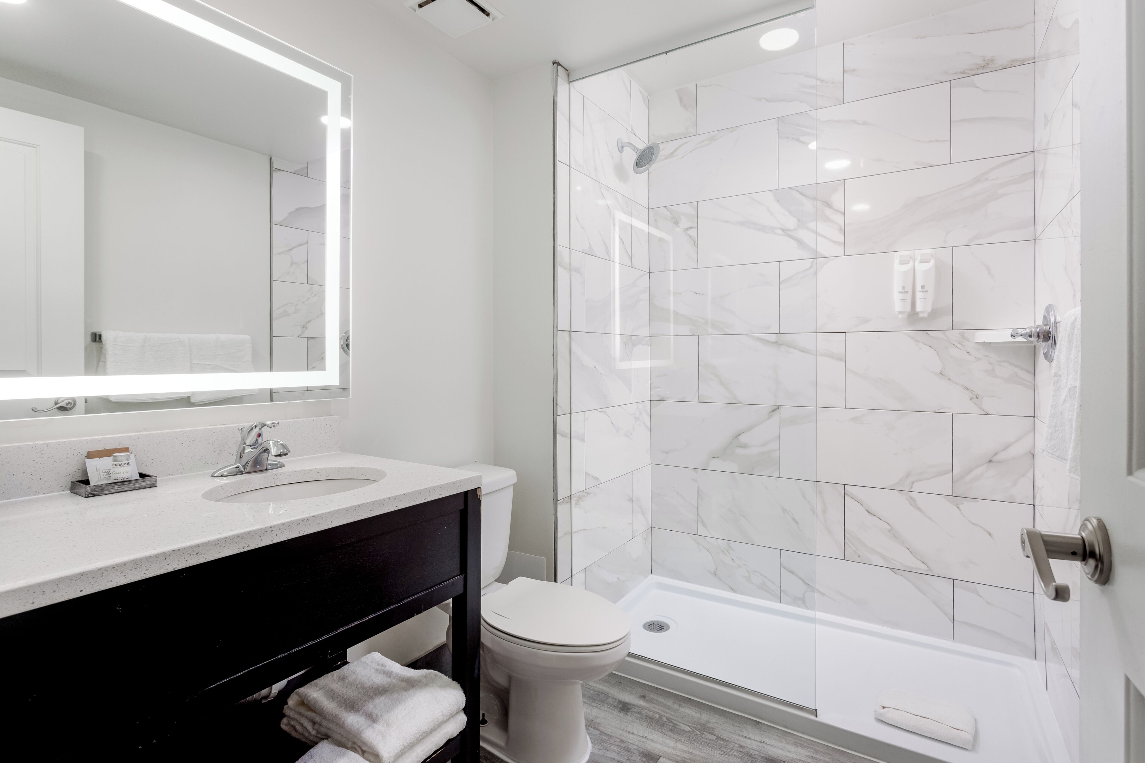 A modern bathroom with a glass shower enclosure, a white sink, and a toilet.