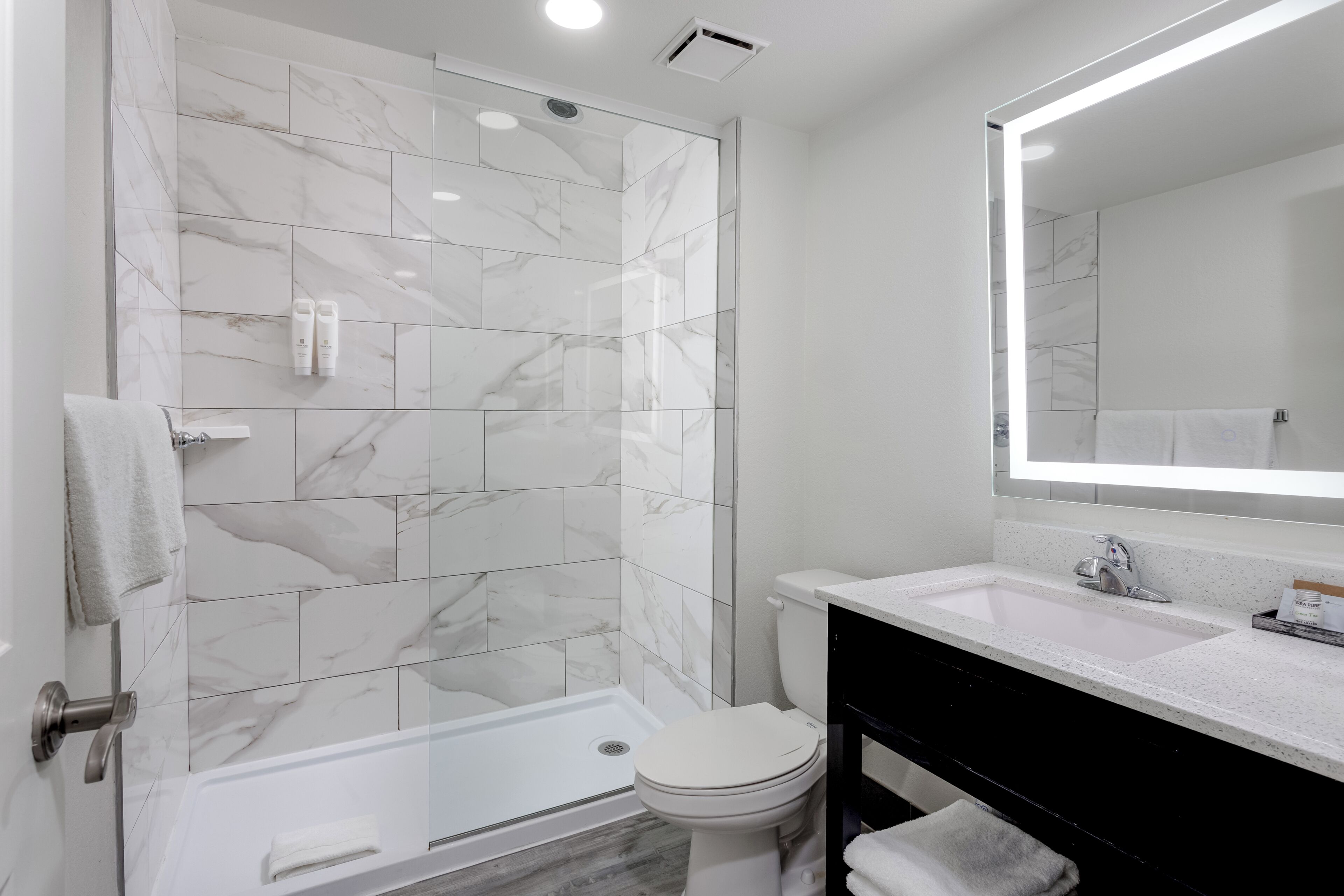 Un bagno moderno con cabina doccia in vetro, un water bianco e un mobile lavabo con specchio.