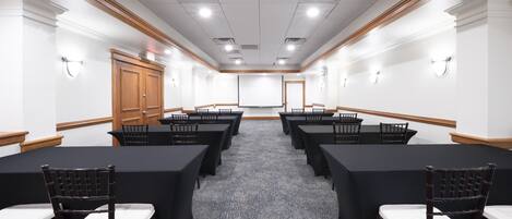 A conference room with a long table, chairs, and a projector screen.