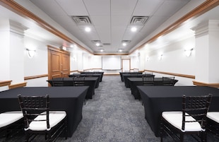 A conference room with a long table, chairs, and a projector screen.