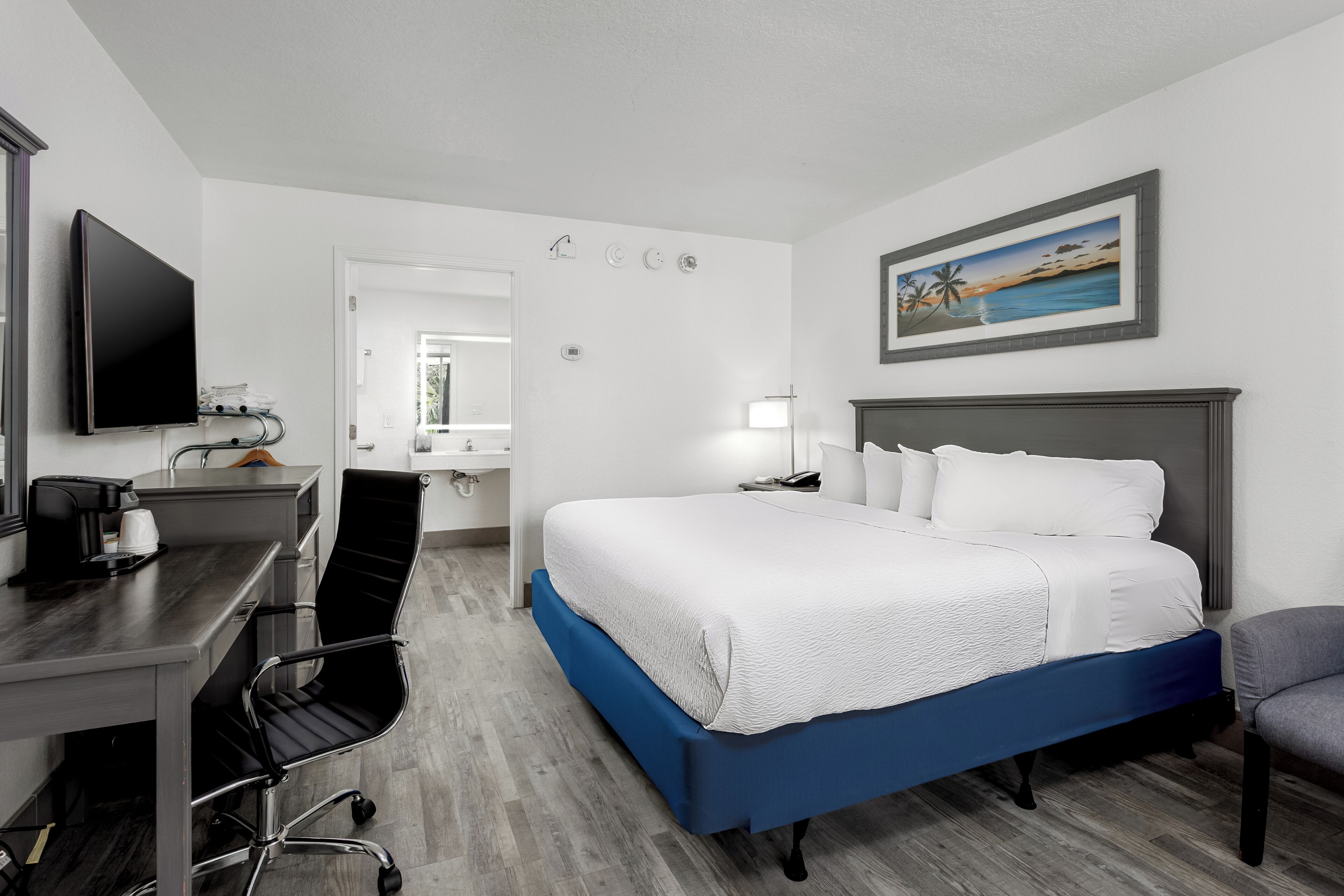 Una habitación de hotel con cama, escritorio, silla y televisión.