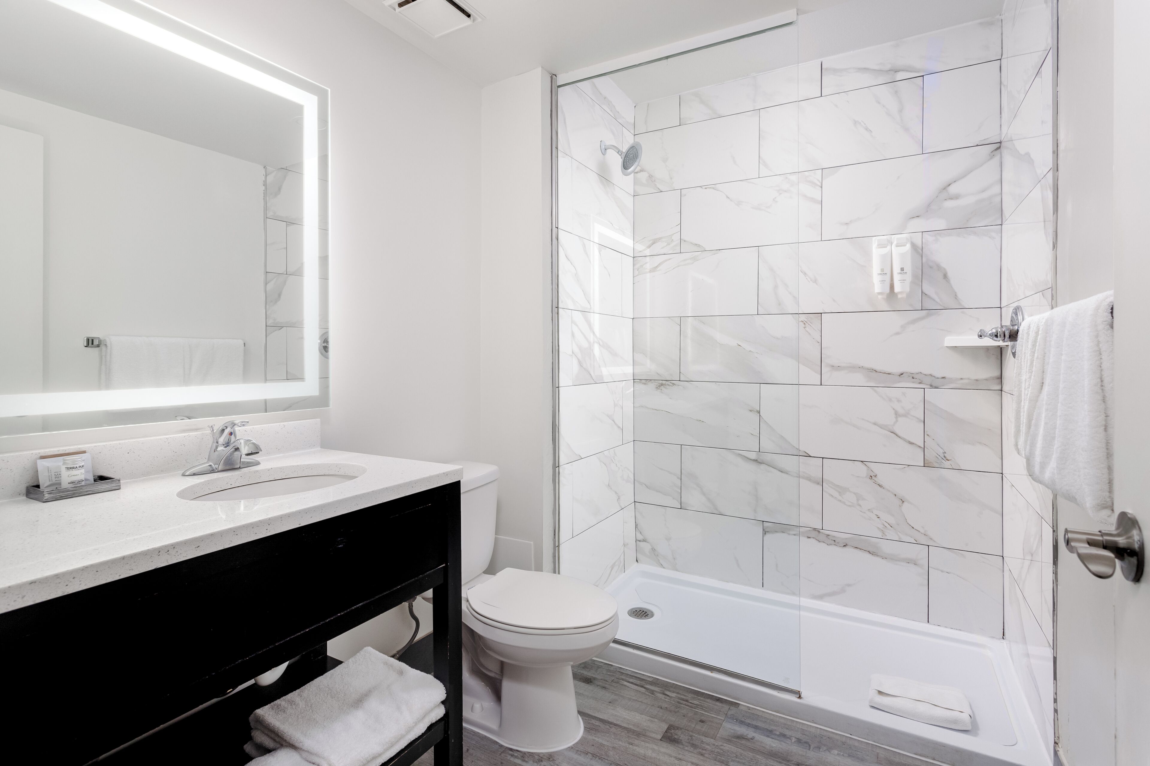 Baño con lavamanos blanco, un espejo, inodoro y zona de ducha.