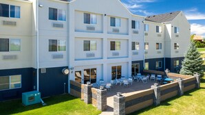 A multi-story hotel with a patio area featuring outdoor seating and a small Christmas tree. - Fairfield Inn & Suites by Marriott Spearfish (Spearfish)