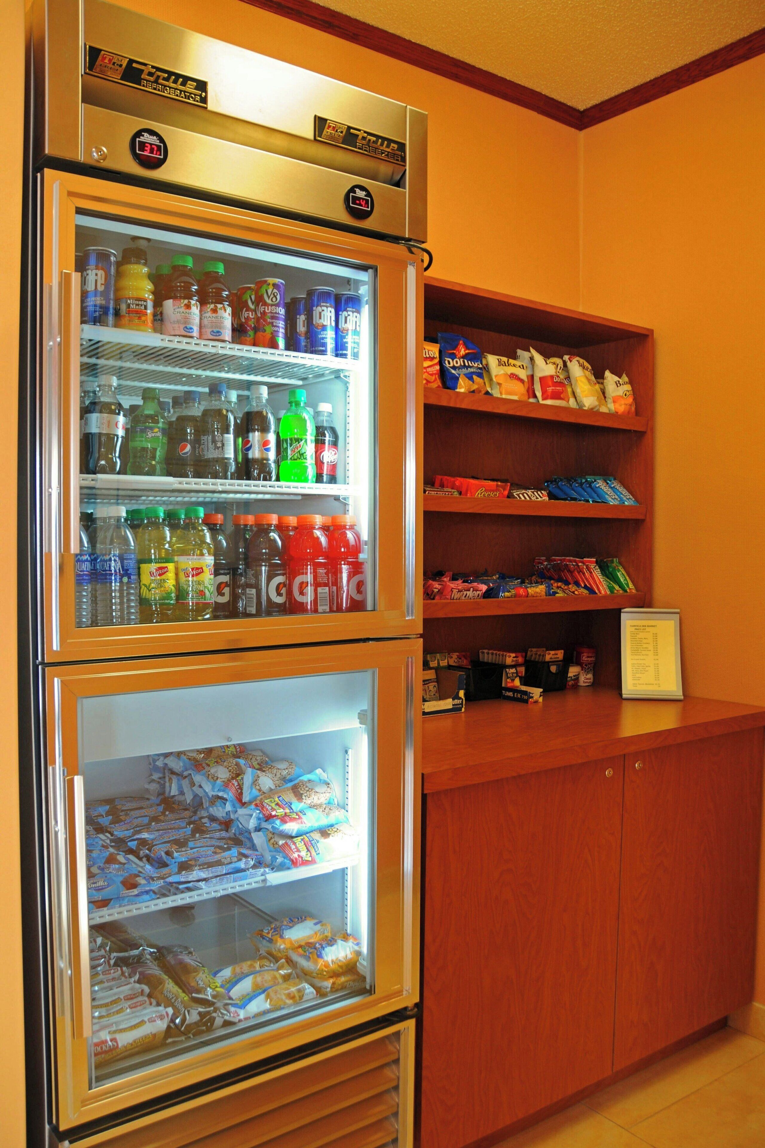 A vending machine with a variety of drinks and snacks, and a wooden shelf with packaged goods.