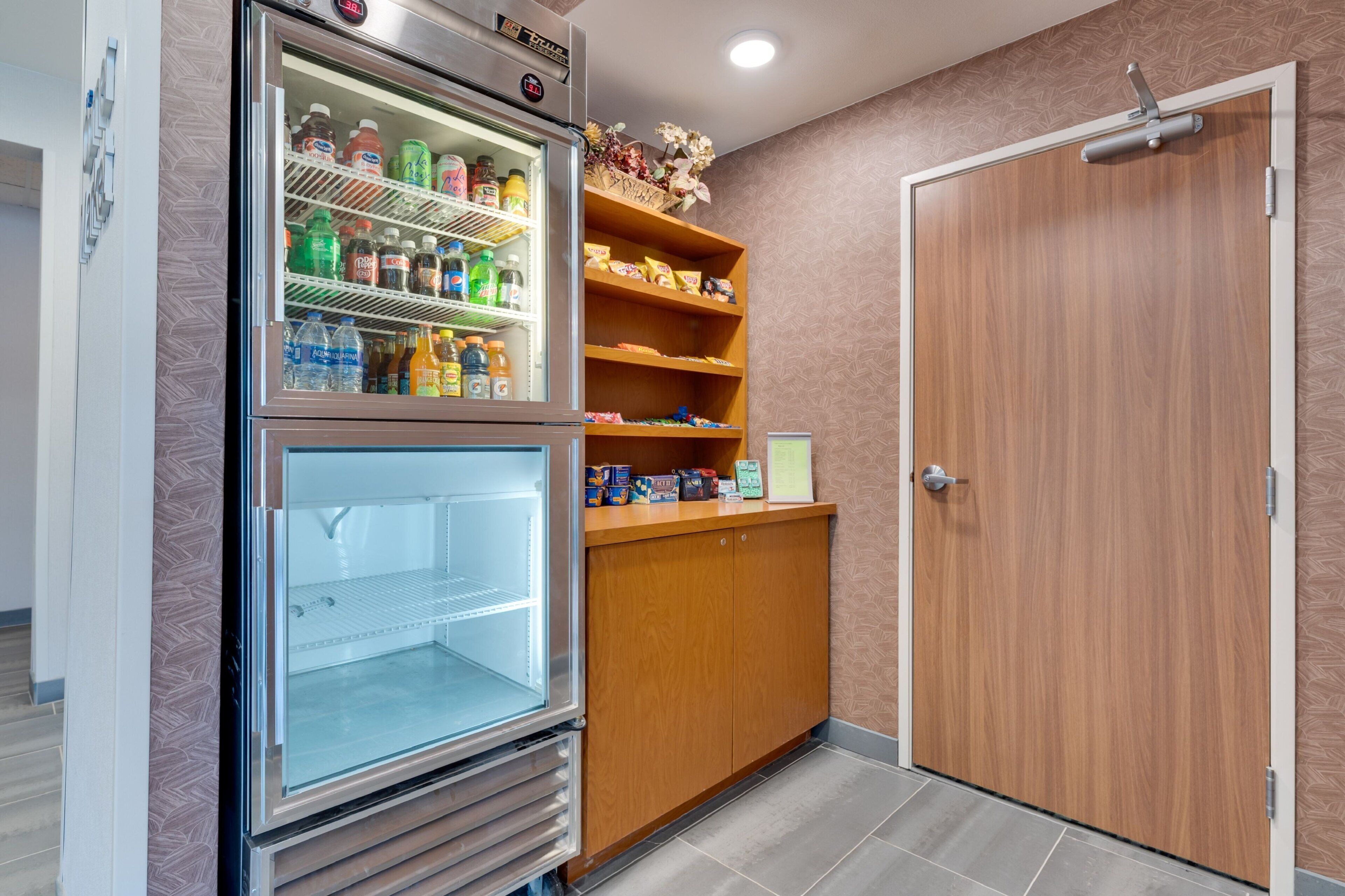 Habitación de hotel con minibar, un mueble de madera y una puerta.