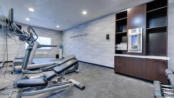 A fitness center with treadmills, a wall-mounted water dispenser, and a storage cabinet.