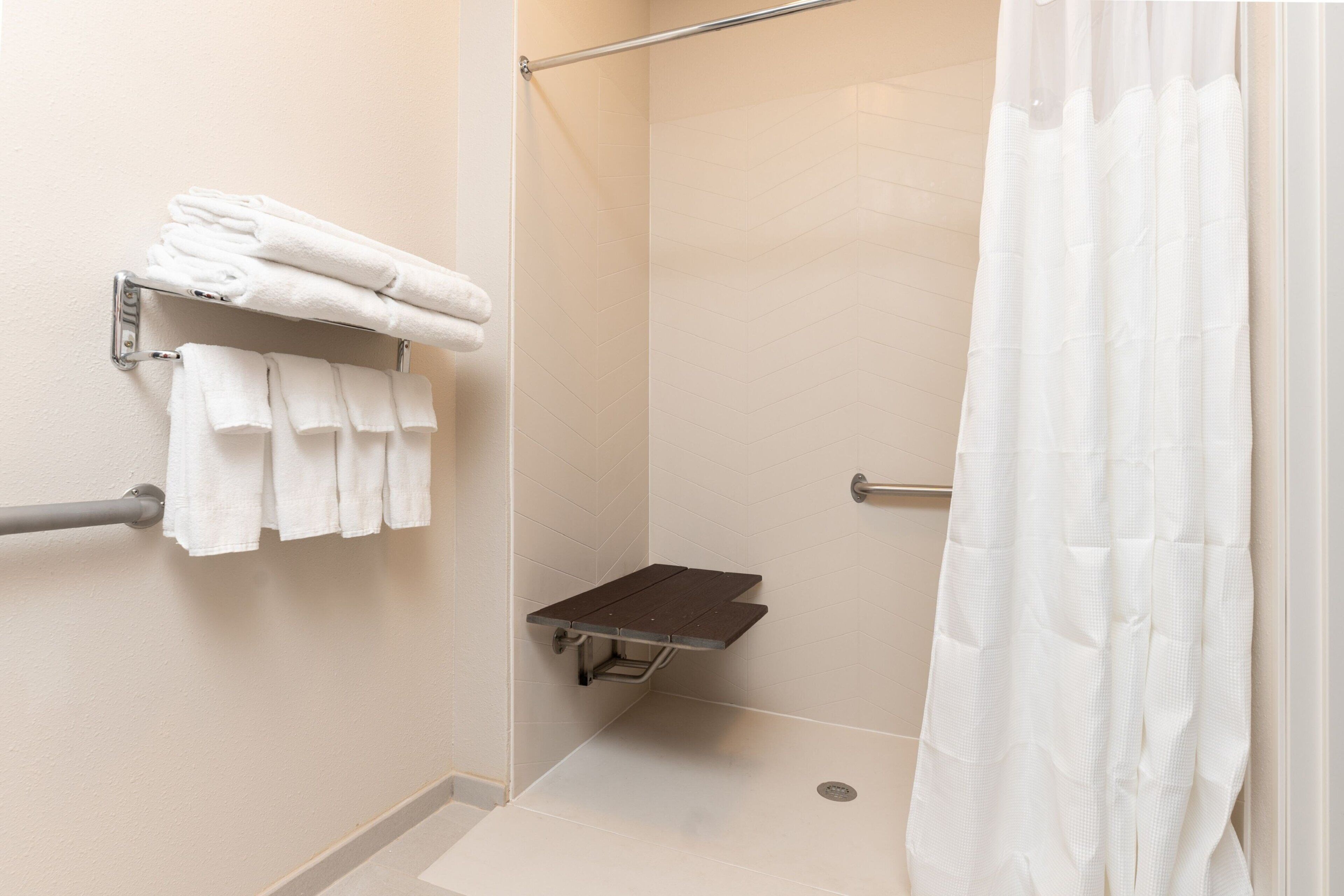 A shower area with a towel rack, a grab bar, and a shower curtain.