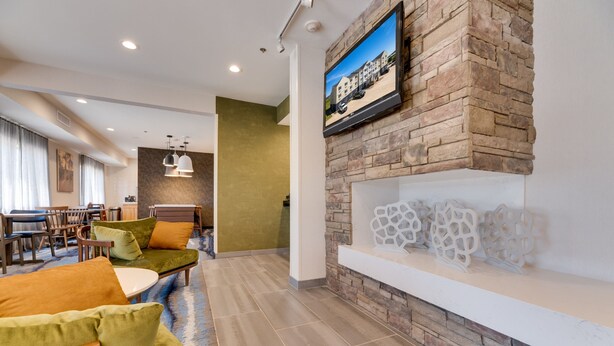 A modern lobby with a stone fireplace, comfortable seating, and a television mounted on the wall. - Fairfield Inn & Suites by Marriott Spearfish (Spearfish)