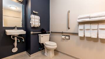 Une salle de bain moderne avec un lavabo, des toilettes et des barres d’appui, le tout de couleur blanche.