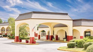 Um hotel com área externa coberta, várias arcadas e estacionamento.