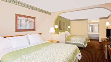 A hotel room with two beds, a television, a desk, and a window.