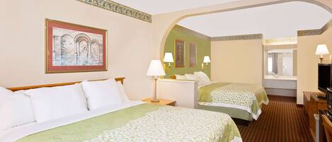 A hotel room with two beds, a television, a desk, and a window.