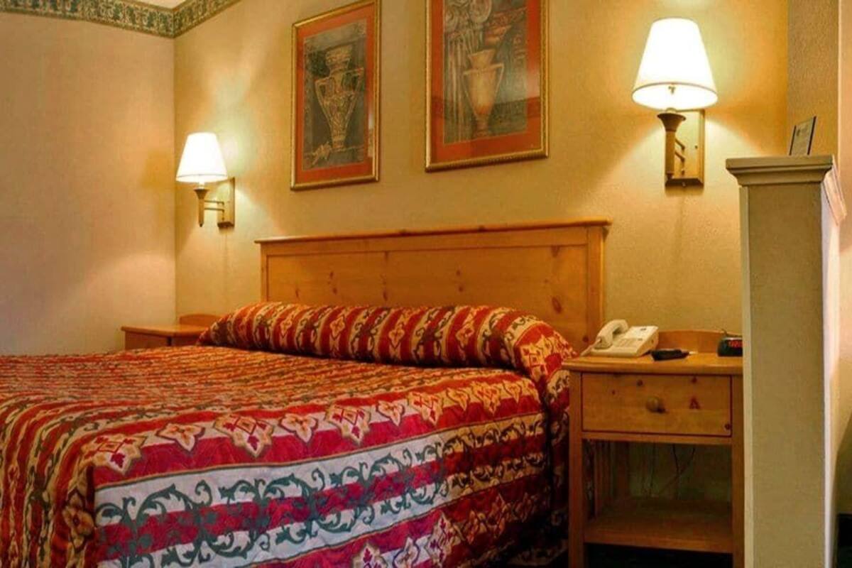 A hotel room with a bed, bedside lamps, a nightstand, and a telephone.