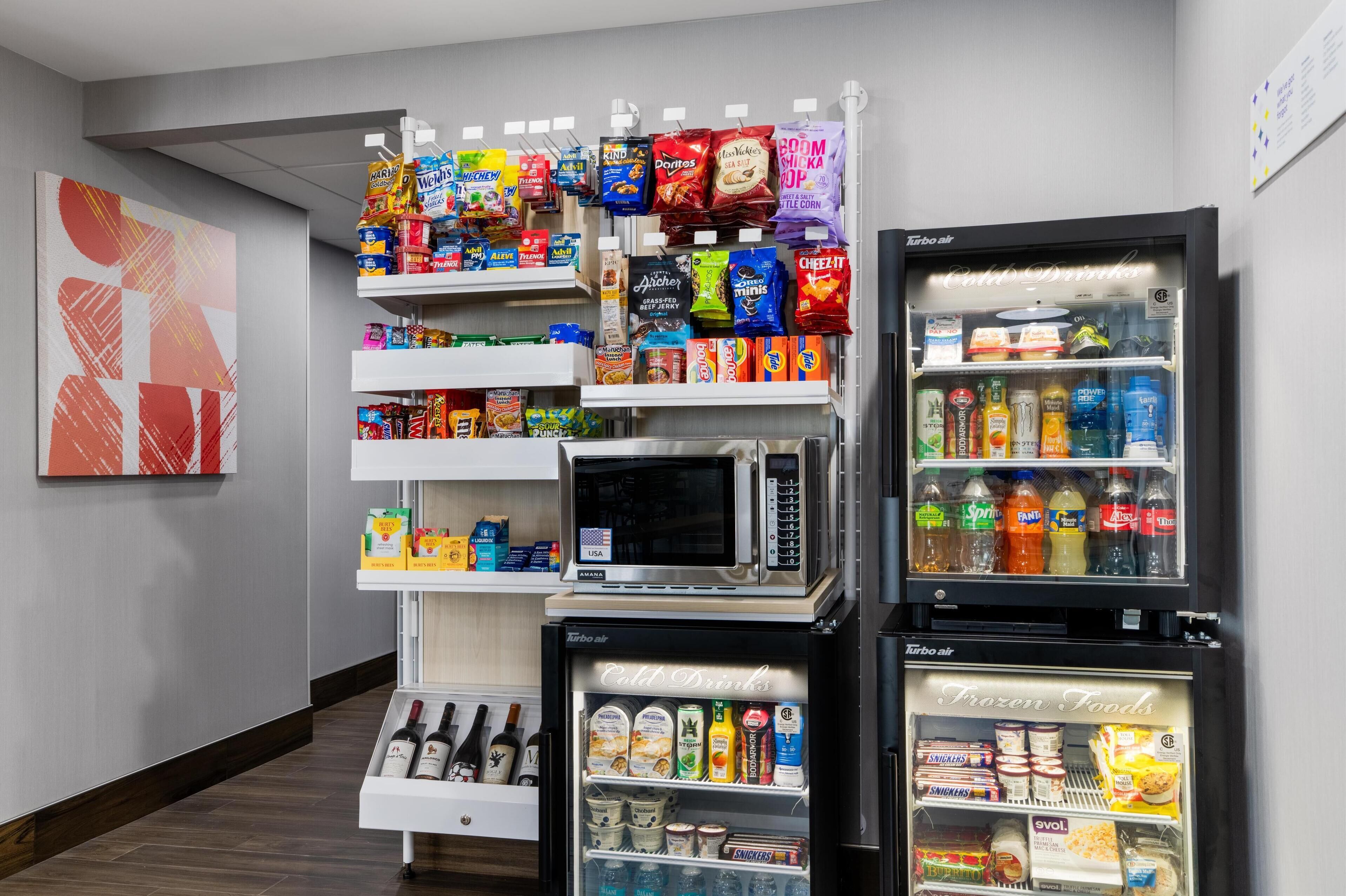 Una macchina distributrice con snack e bevande, un forno a microonde e un mini-frigorifero con bevande e snack.