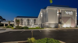 A modern hotel with a 'spark by Hilton' sign, a parking lot, and a well-lit entrance.